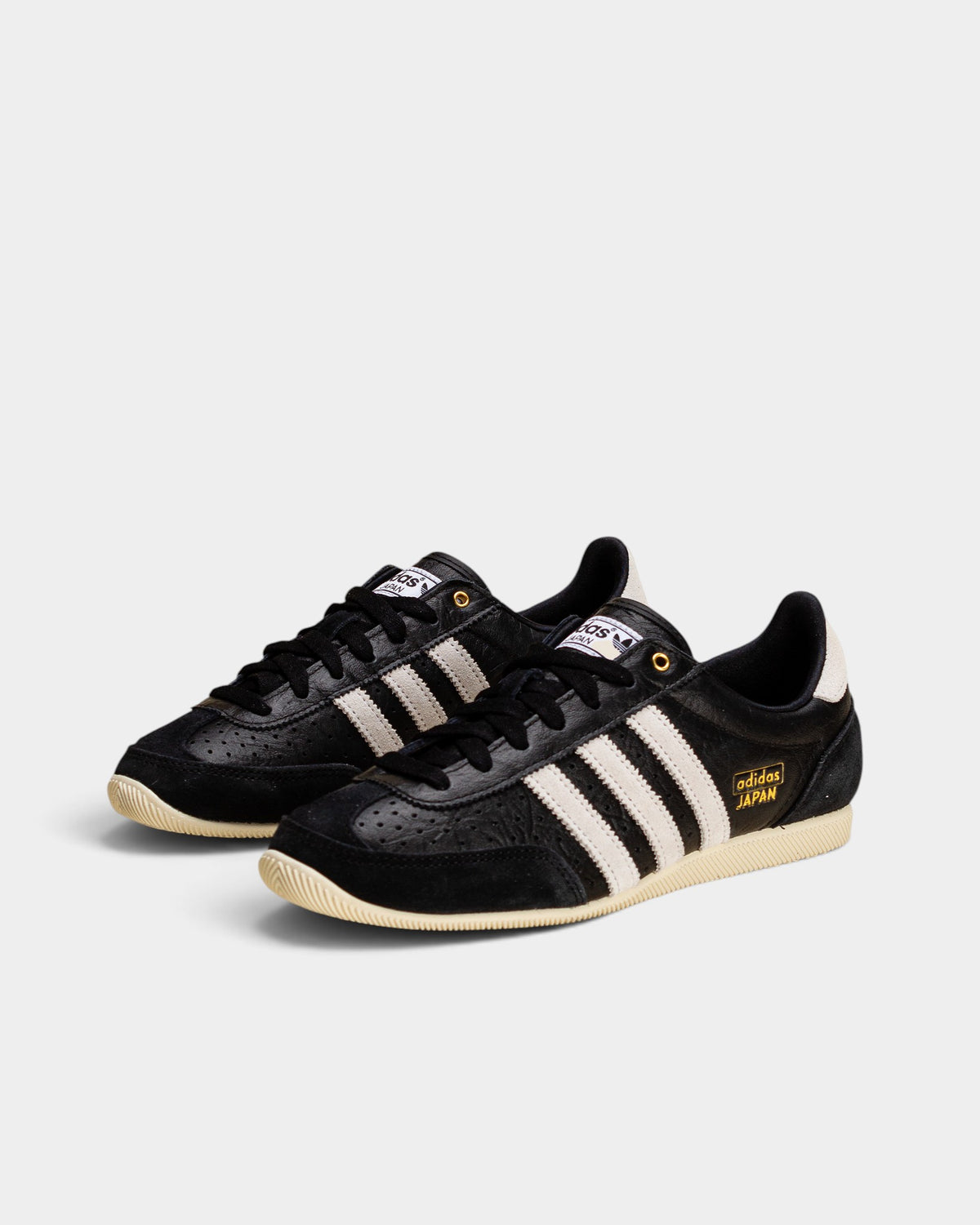 Lockwood Avenue adidas Japan women's black perforated leather trainers with white stripes and gold accents.