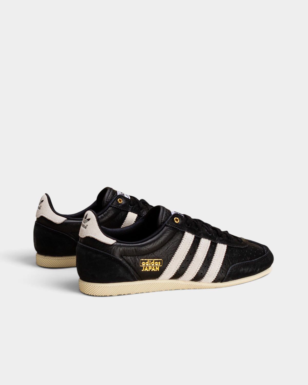 Lockwood Avenue adidas Japan women's black perforated leather trainers with white stripes and gold logo detailing.