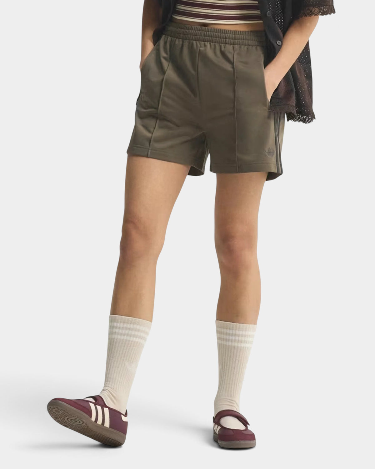 Lockwood Avenue adidas Firebird olive green tricot shorts with 3-Stripes, worn by a model with socks and sneakers.