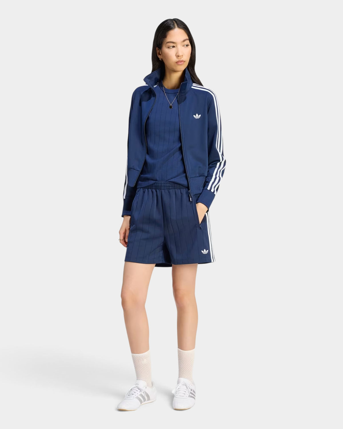 Lockwood Avenue model wearing adidas night indigo pinstripe Firebird shorts with matching track jacket and sneakers.