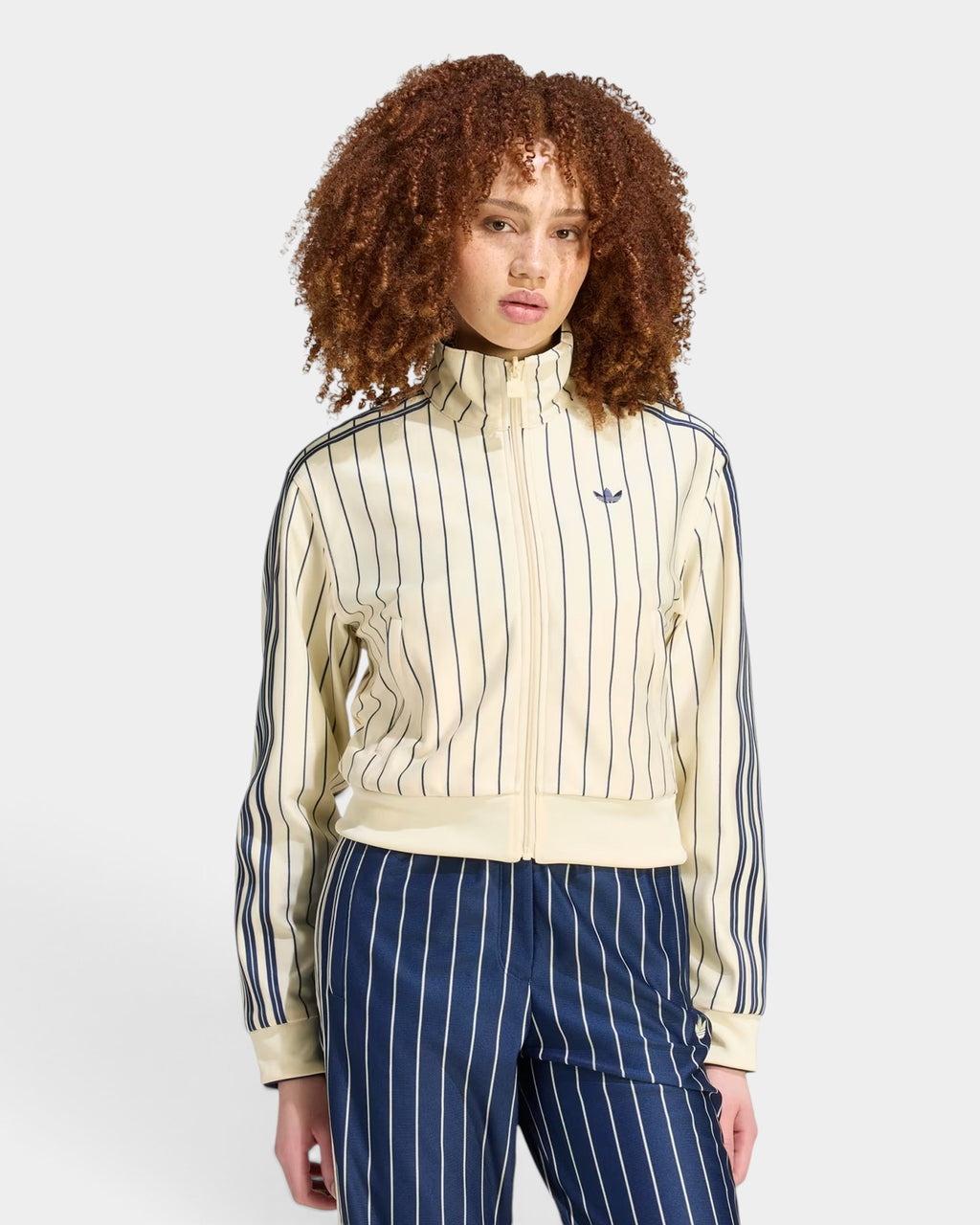 Lockwood Avenue model wearing a cream and navy pinstriped adidas reversible track top with a full zip and collar.