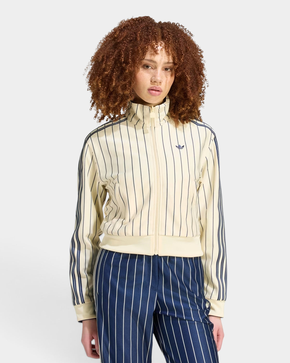 Lockwood Avenue model wearing a cream and navy pinstriped adidas reversible track top with a full zip and collar.
