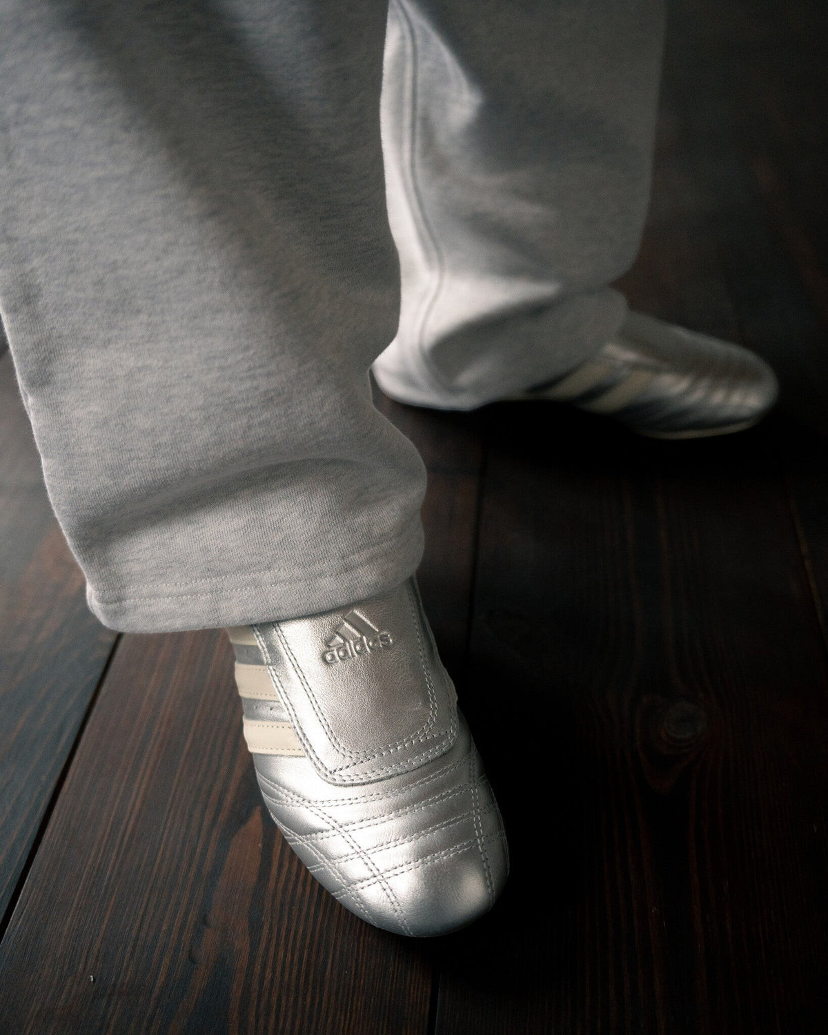 Lockwood Avenue adidas Taekwondo metallic silver leather slip-on sneakers with off-white stripes on a wooden floor