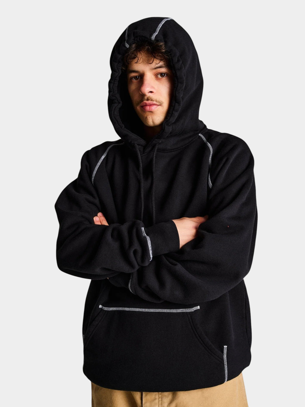A model wearing a black Lockwood Avenue cotton hoodie with white flatlock stitching and a kangaroo pocket.