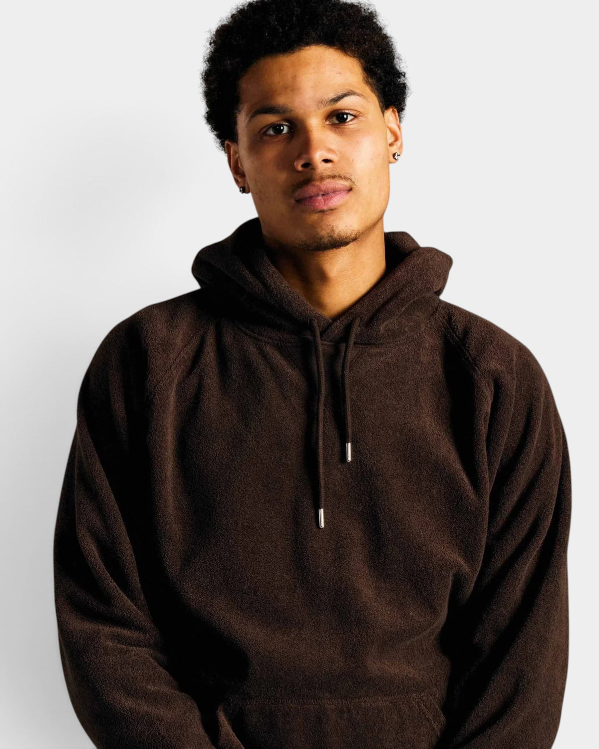 Lockwood Avenue model wearing a brown cotton terry hooded sweatshirt with a drawstring hood and silver aglets.