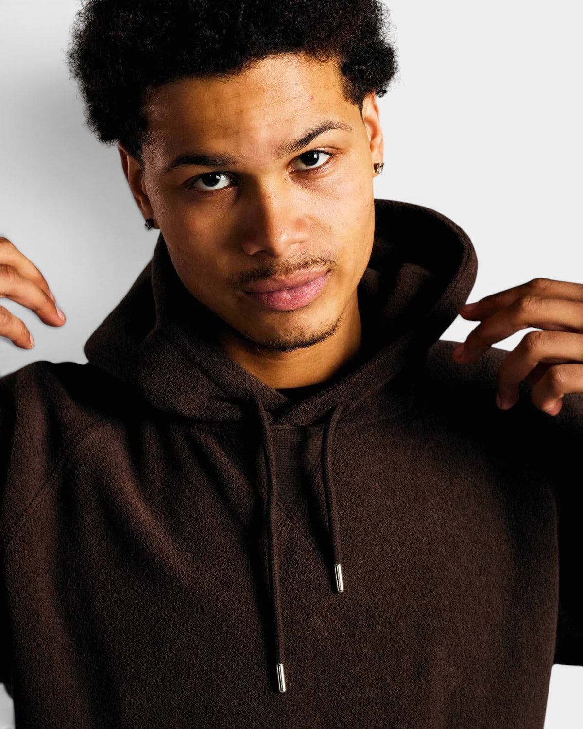 Lockwood Avenue model wearing a dark brown Pop Trading Company cotton terry hooded sweatshirt with silver aglets