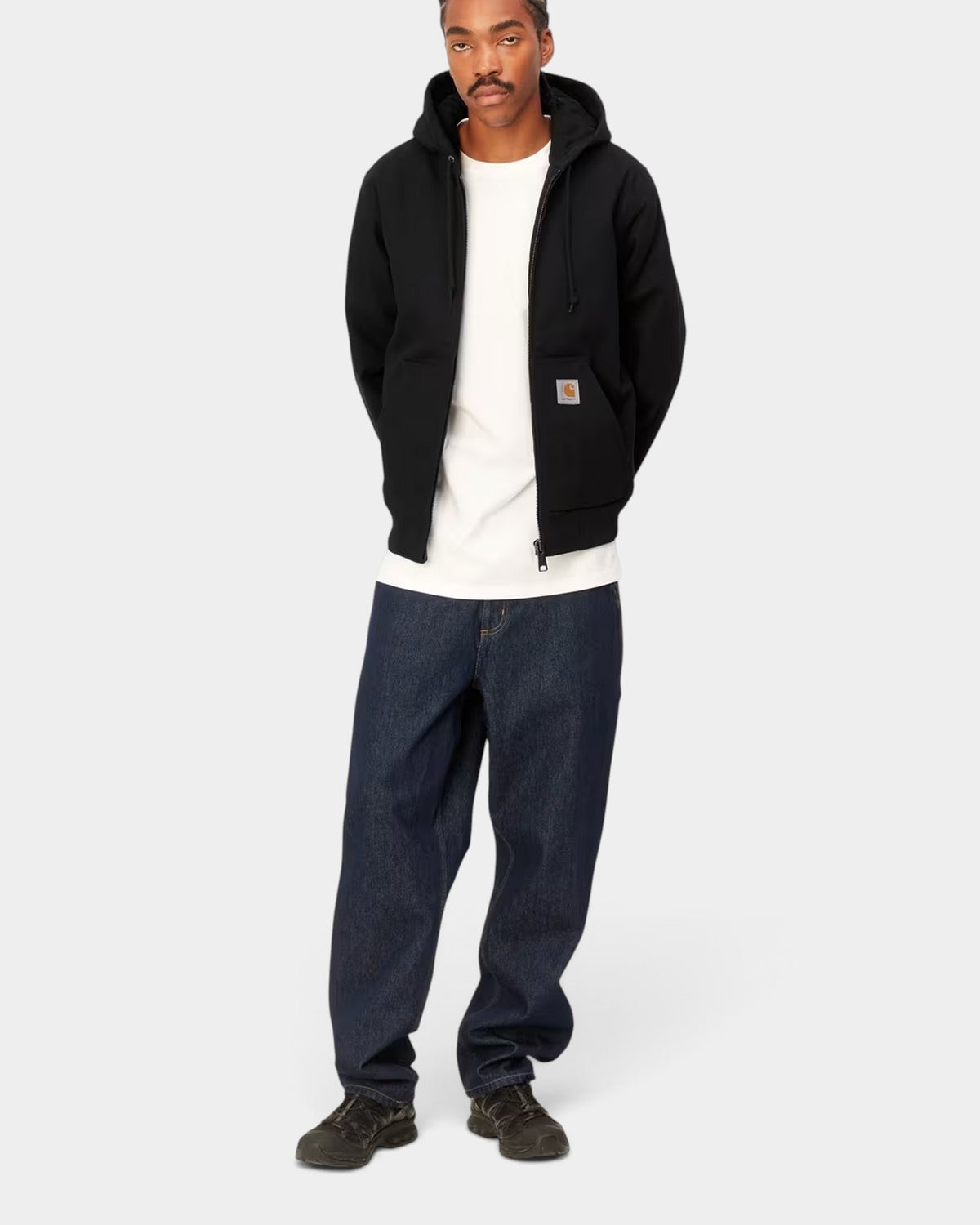 Model wearing a black Carhartt Active Winter Jacket by Lockwood Avenue with a hood, kangaroo pocket, and square label.