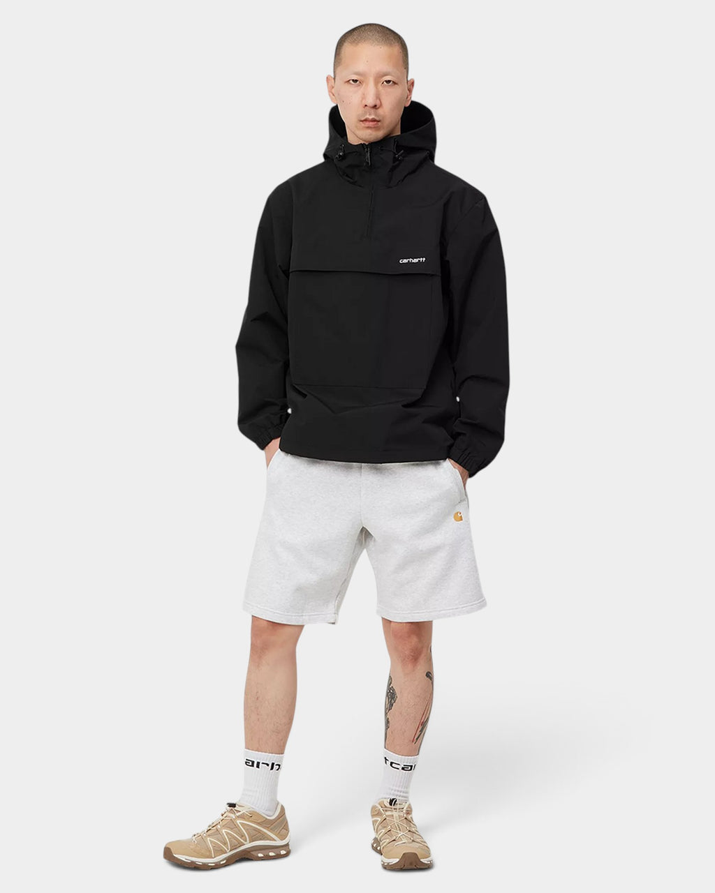 Lockwood Avenue model wearing a black Carhartt water-repellent nylon windbreaker pullover with an adjustable hood.