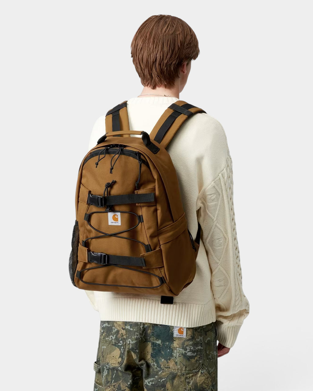 Lockwood Avenue Carhartt Kickflip brown skate backpack with front board straps worn by a model in a white sweater