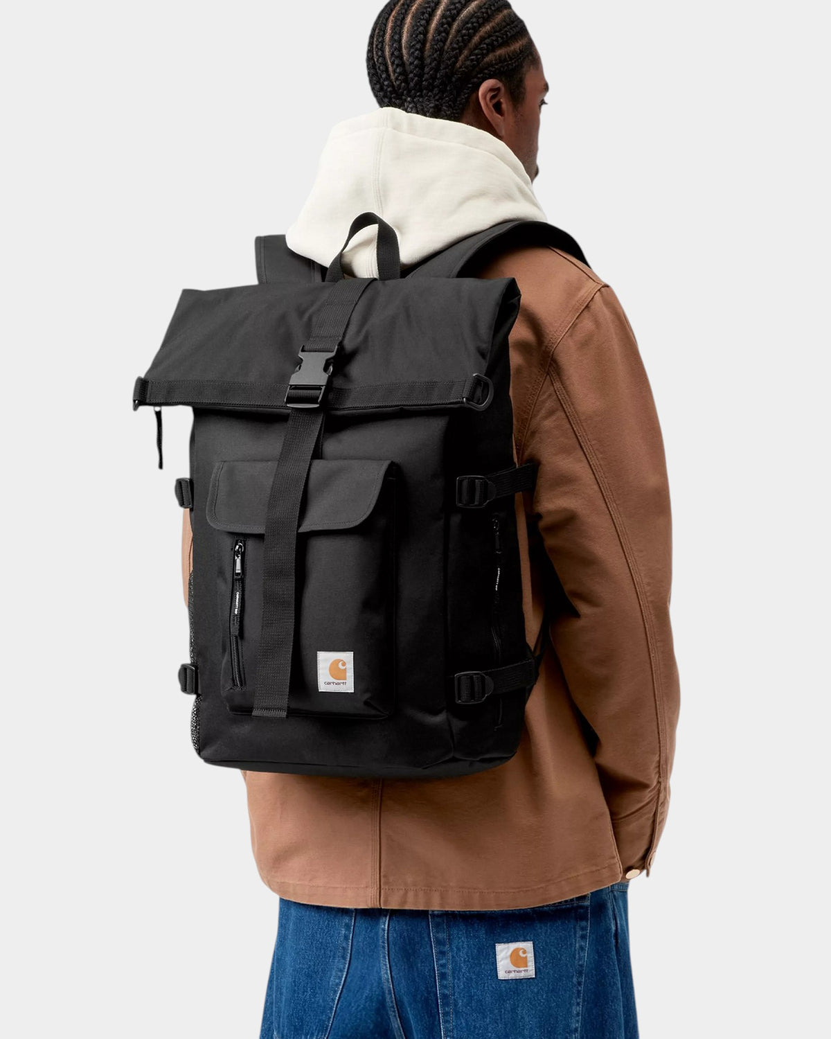Lockwood Avenue Carhartt Philis black recycled polyester flap-top backpack worn by a person from a side angle