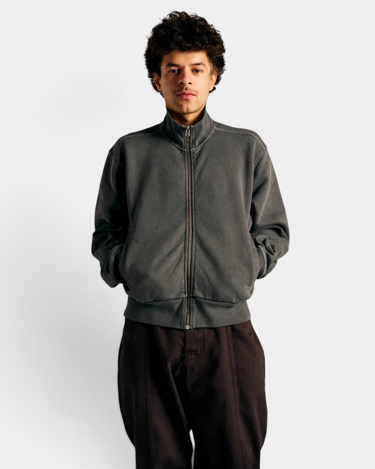 Lockwood Avenue model wearing a charcoal garment-dyed cotton full zip sweatshirt with silver hardware and front pockets