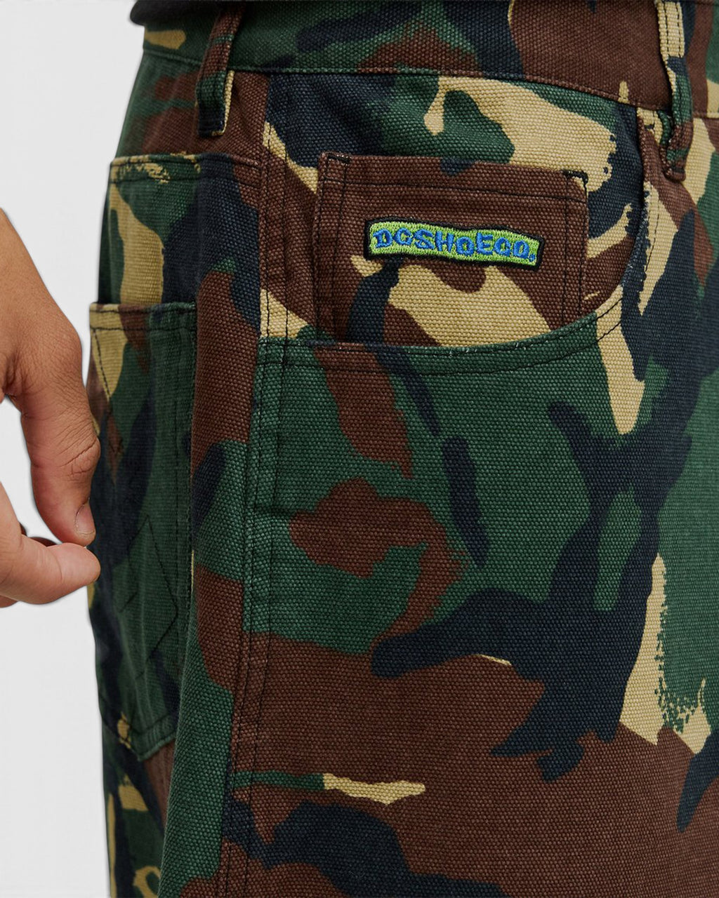 Close-up of Lockwood Avenue DC Barrel canvas pants in camouflage print with a green and blue embroidered logo patch.