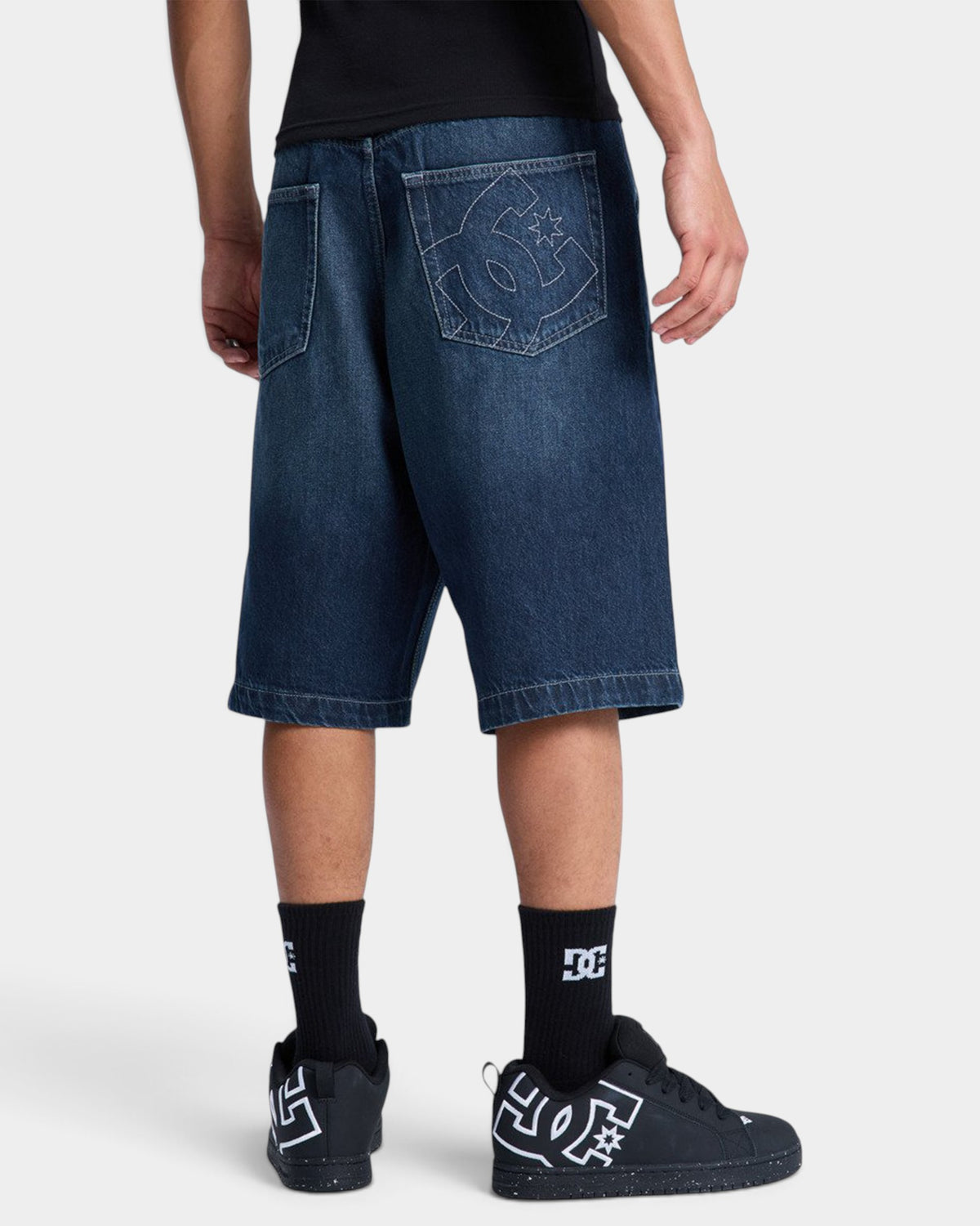 Lockwood Avenue DC Shoes baggy dark denim jorts with embroidered logo on back pocket, worn by a model.
