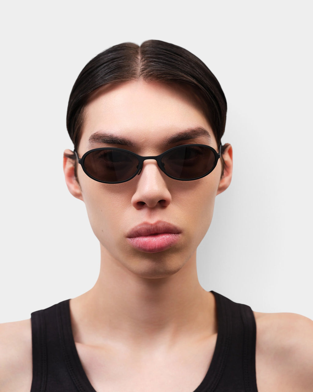 Lockwood Avenue Flatlist Cohen sunglasses in solid black with oval frames worn by a model against a white background.