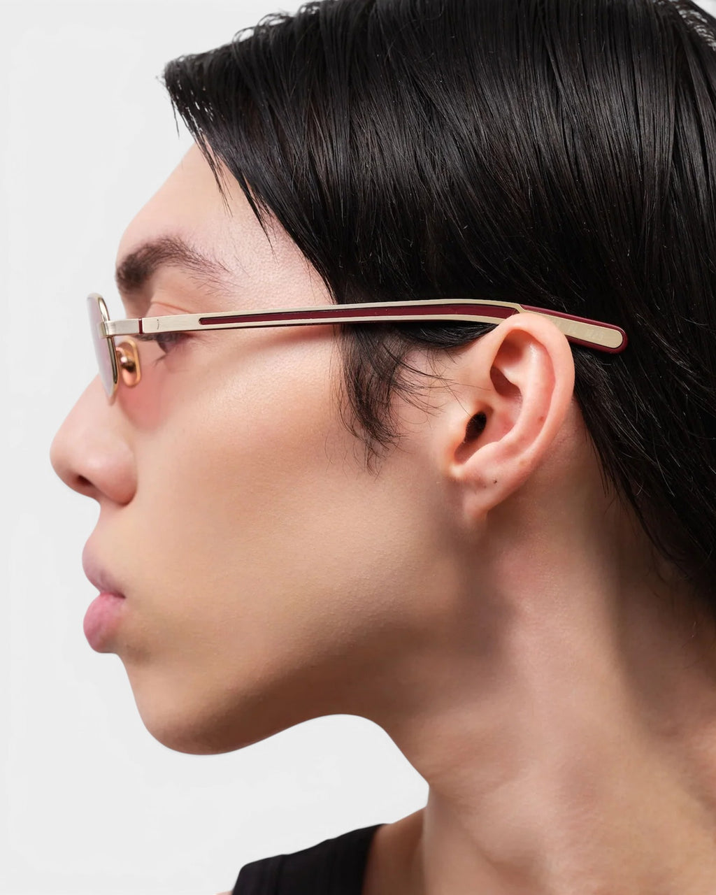 Lockwood Avenue Flatlist Sting sunglasses in brushed light gold with pink lenses worn by a model in profile view.