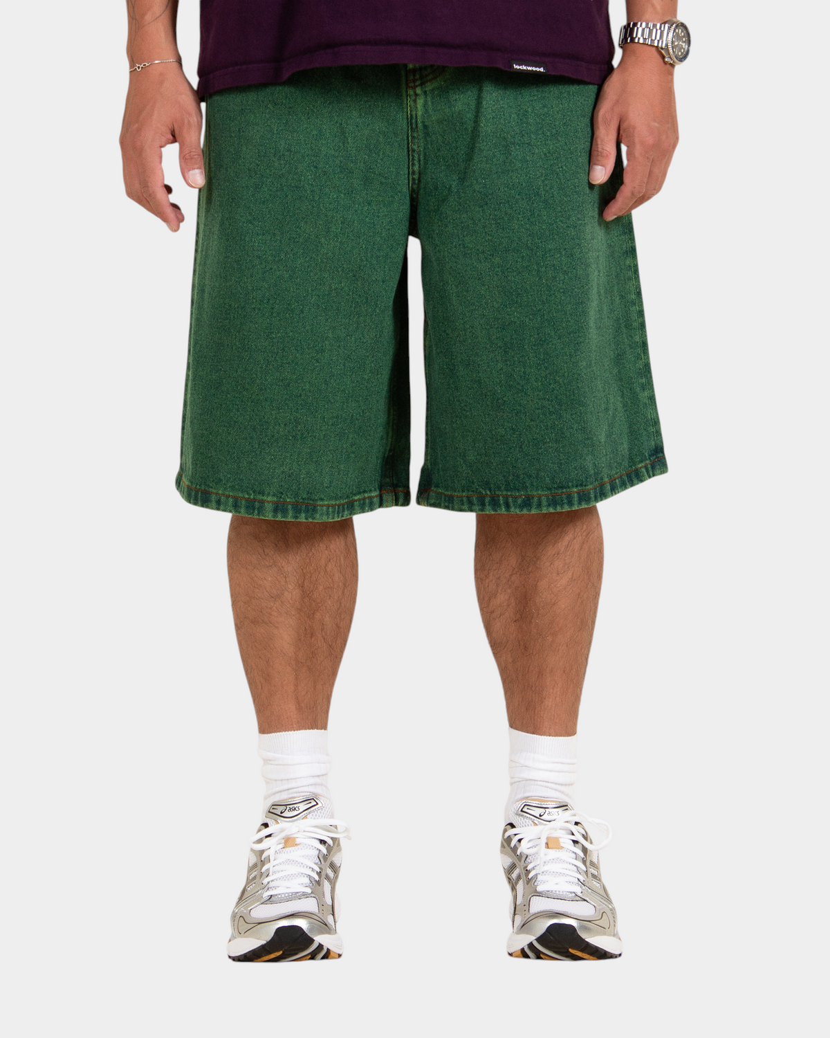 Lockwood Avenue baggy denim shorts in overdye green cotton with a long fit and button fly, worn by a model.