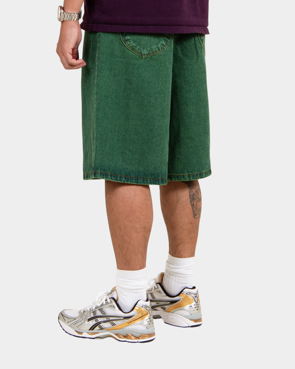 Lockwood Avenue baggy denim shorts in overdye green cotton with angular back pockets, worn by a model.