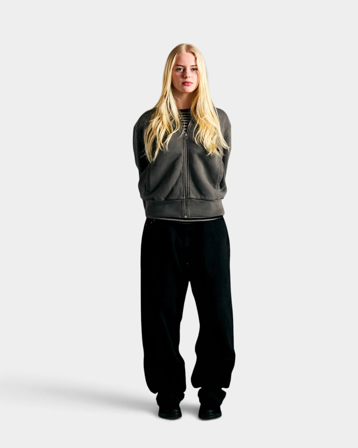 Lockwood Avenue model wearing a grey garment-dyed cotton full-zip sweatshirt with silver hardware and ribbed cuffs.