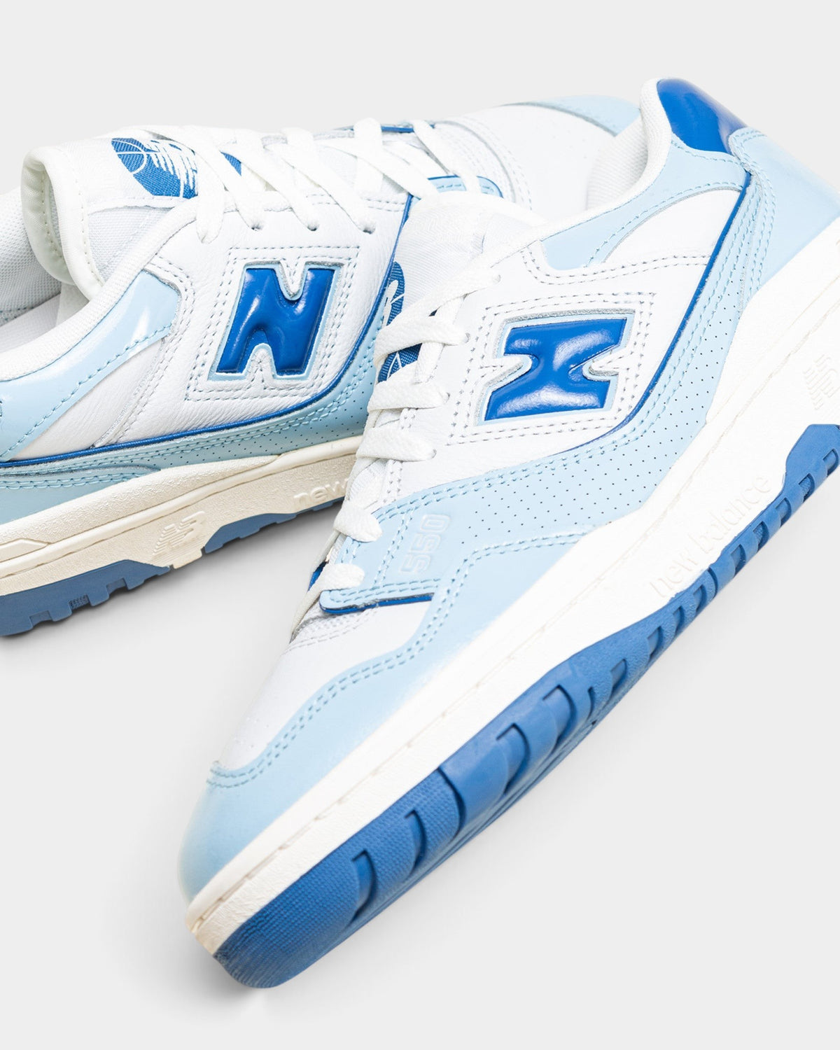 Lockwood Avenue New Balance 550 low-top sneakers in white leather with glossy chrome blue patent leather overlays.
