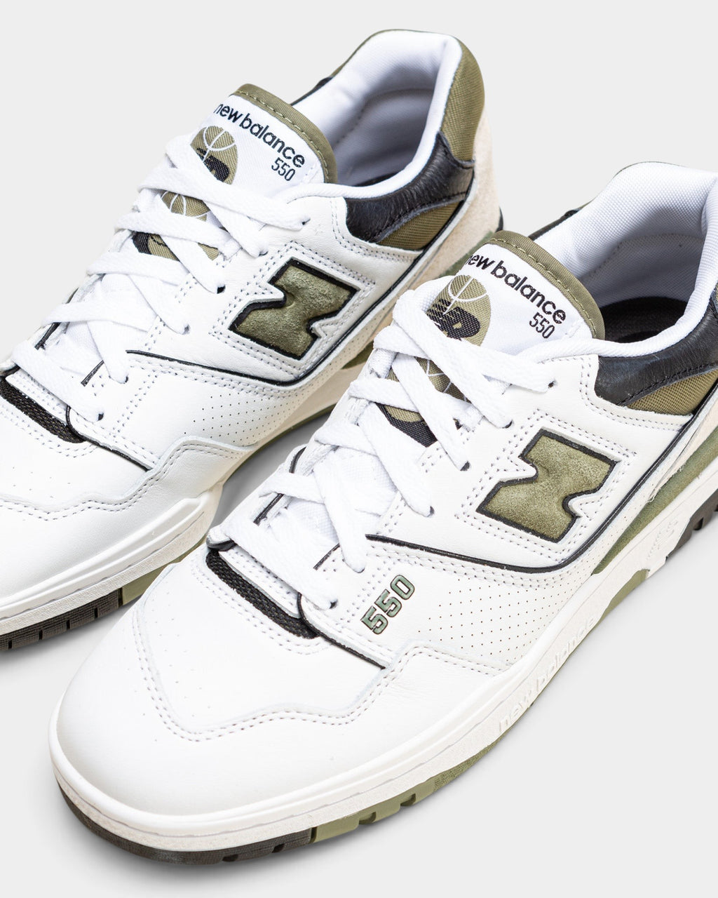 Lockwood Avenue New Balance 550 low-top sneakers in white leather with dark olivine green and black accents.