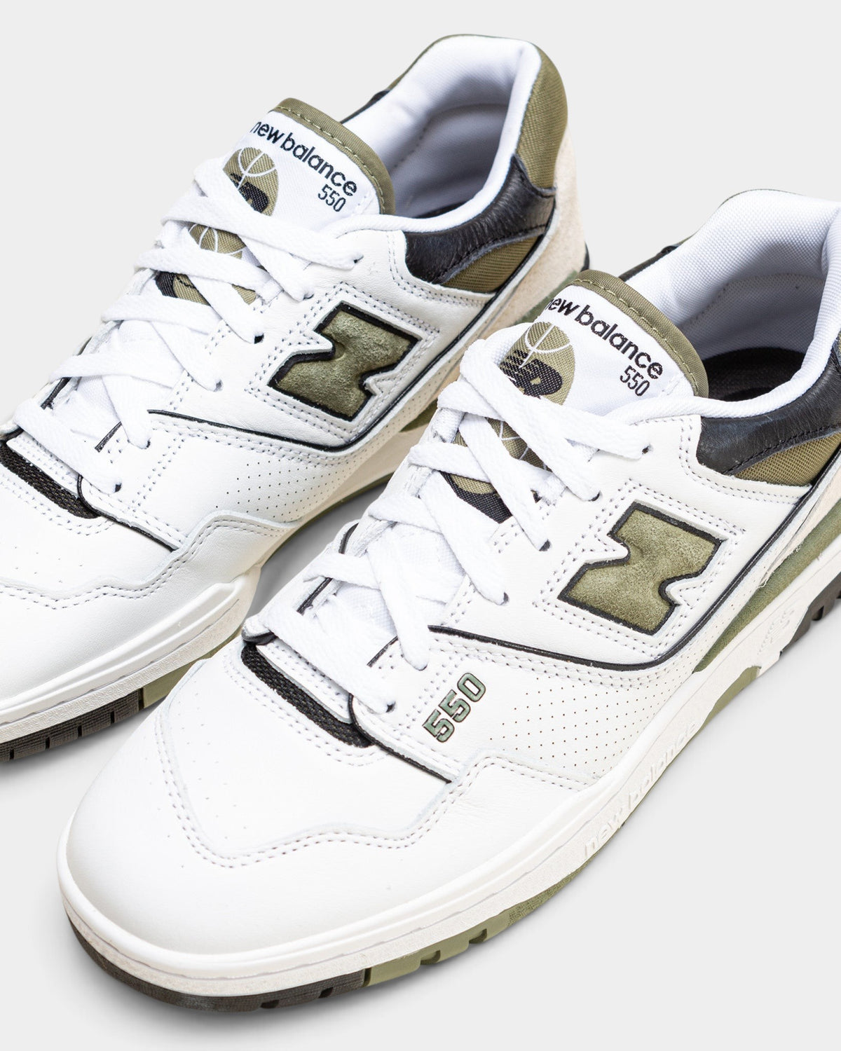 Lockwood Avenue New Balance 550 low-top sneakers in white leather with dark olivine green and black accents.