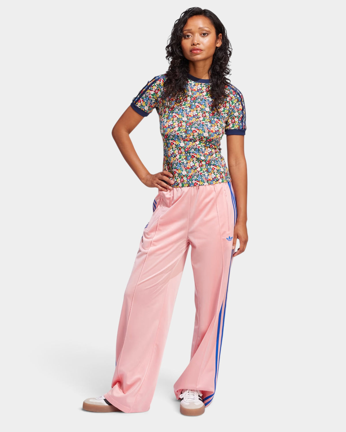 Lockwood Avenue model wearing pink adidas Firebird loose track pants with blue 3-Stripes and a floral print top.