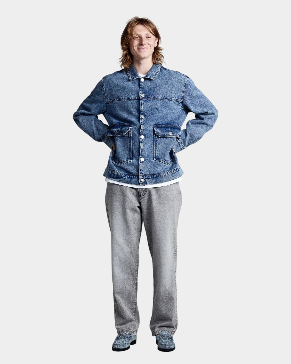 Lockwood Avenue model wearing a blue denim Pop Trading Company DRS jacket with large front pockets and metal buttons