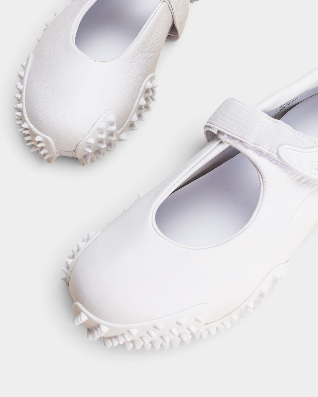Lockwood Avenue Puma Mostro Fey LTH white leather Mary Jane shoes with a single strap and spiked rubber outsole.