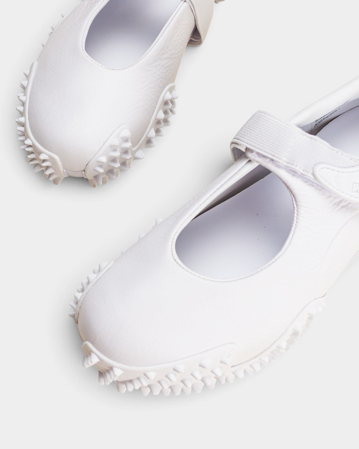 Lockwood Avenue Puma Mostro Fey LTH white leather Mary Jane shoes with a single strap and spiked rubber outsole.