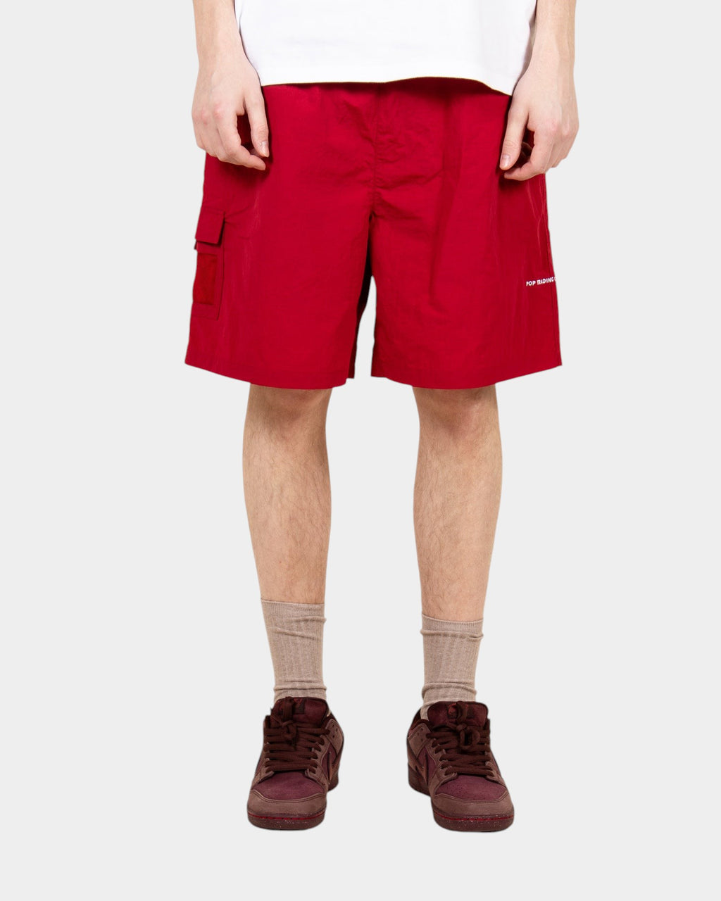 Lockwood Avenue Pop Trading Company red nylon painter shorts with side pocket and white logo on a model