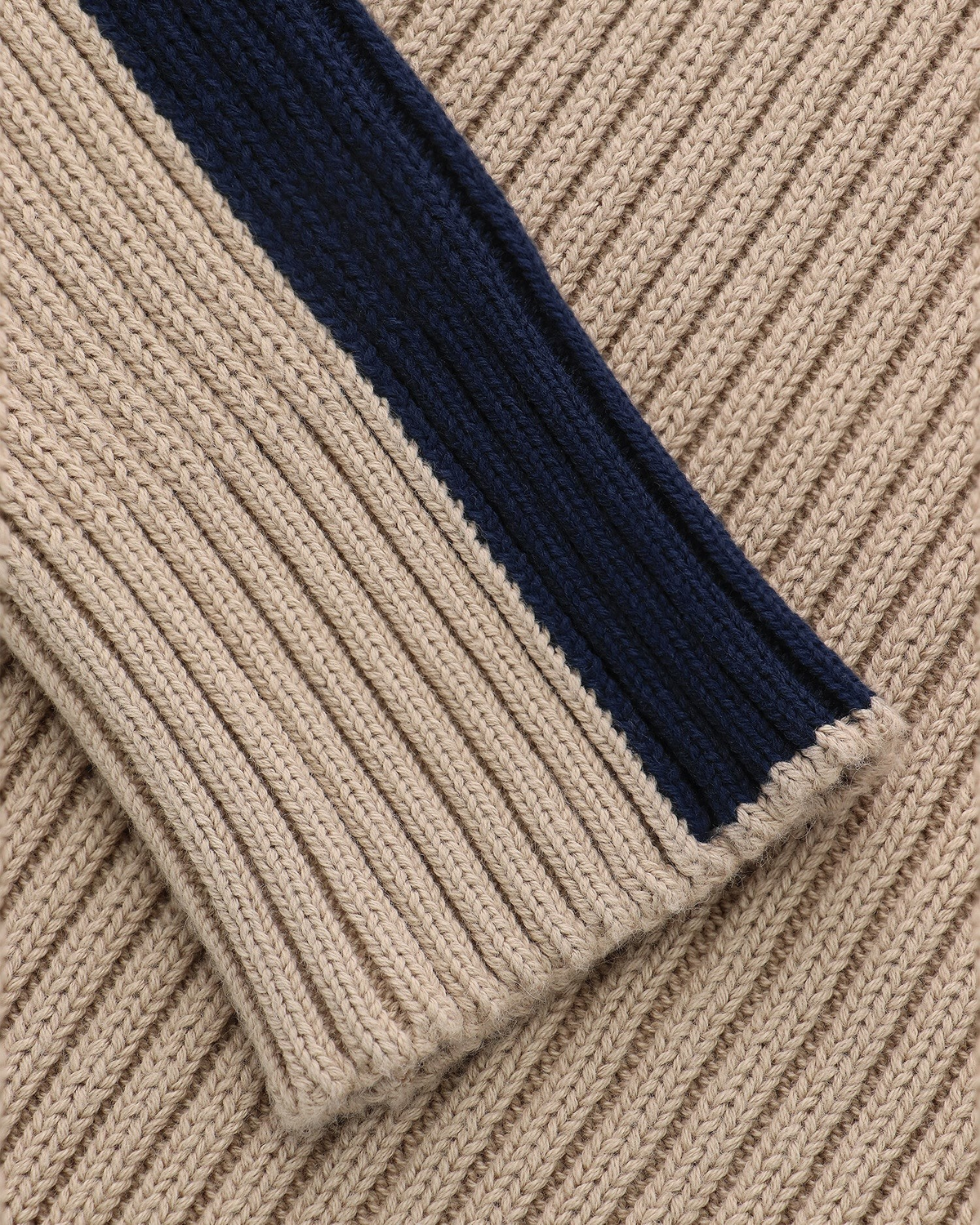 Close-up of a Lockwood Avenue Y2K rib knit sweater in beige cotton with a contrasting navy blue stripe detail.