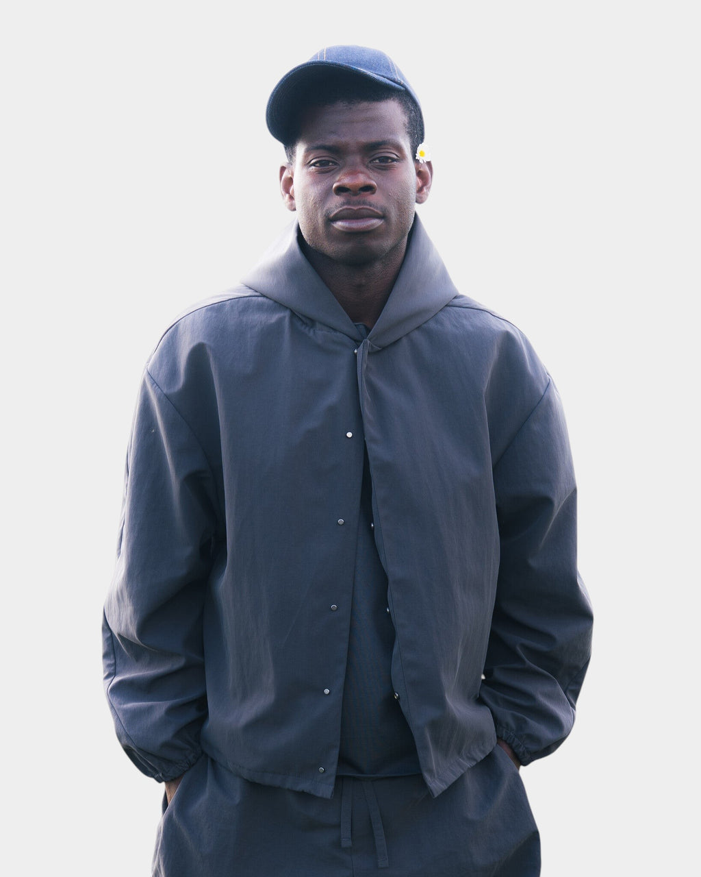 A man wearing a charcoal grey Lockwood Avenue Seventh Orb nylon shell jacket with a snap-button front and hood.