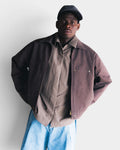 Lockwood Avenue Seventh Worker Jacket in brown cotton with metal zip, worn by a man in a cap and light blue jeans.