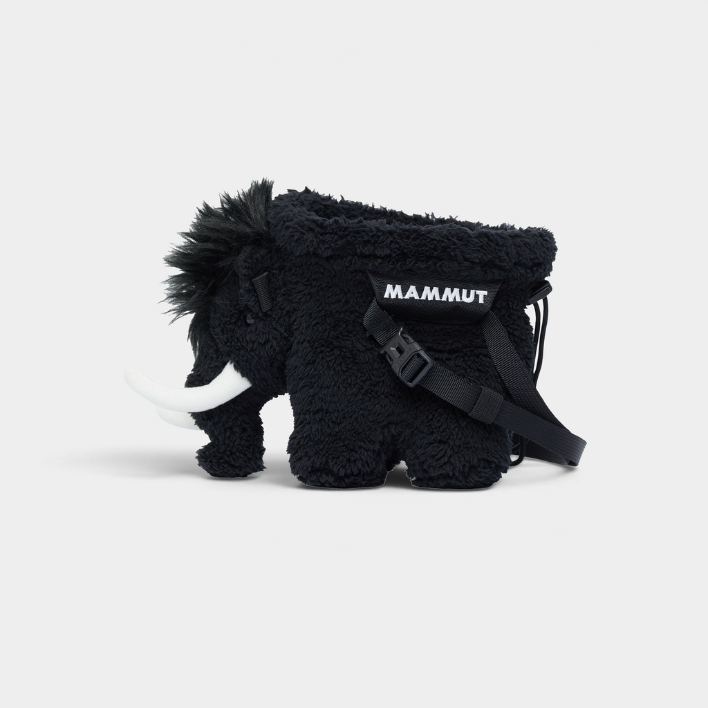 Mammut Fluffy Chalk Bag in black, a fleecy mammoth-shaped climbing chalk bag seen side on, with white tusks and a black MAMMUT webbing belt across its flank