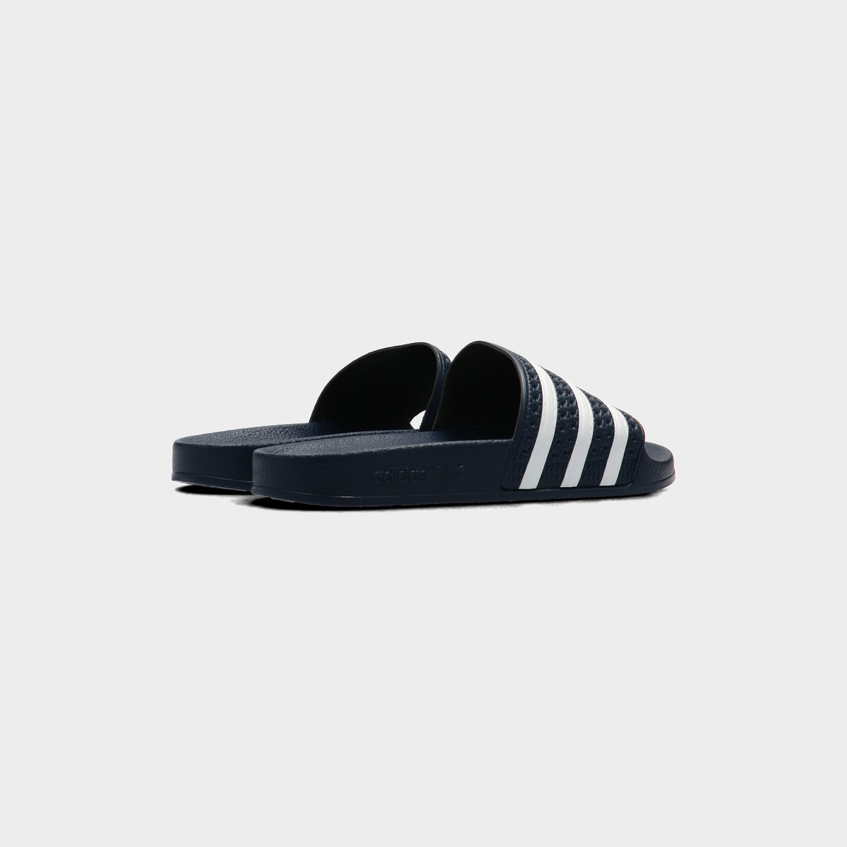Lockwood Avenue pair of adidas Adilette Slides in AdiBlu navy, rear view showing the open heel and white 3-Stripes