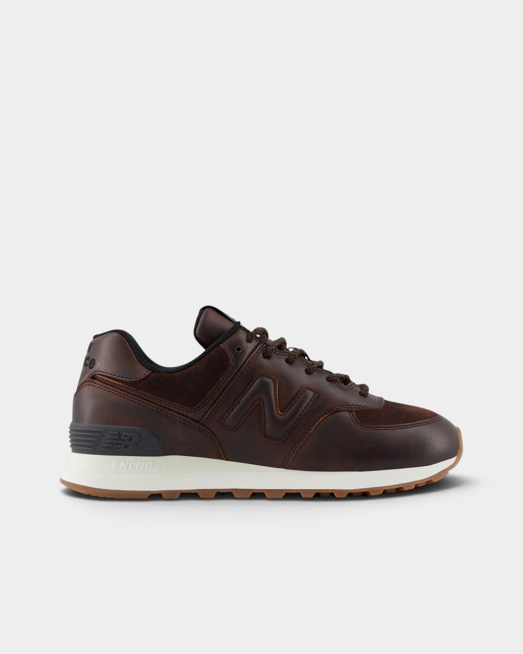 New Balance 574 Shoes in Pumpernickel/Sea Salt, side profile: dark brown leather upper with a tonal N logo, a grey heel counter and a cream midsole over a gum outsole
