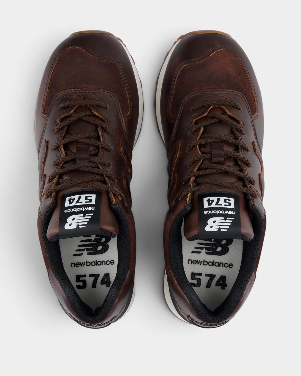 New Balance 574 Shoes in Pumpernickel/Sea Salt, pair from above with brown laces, white 574 tongue labels and a dark lining around the collar