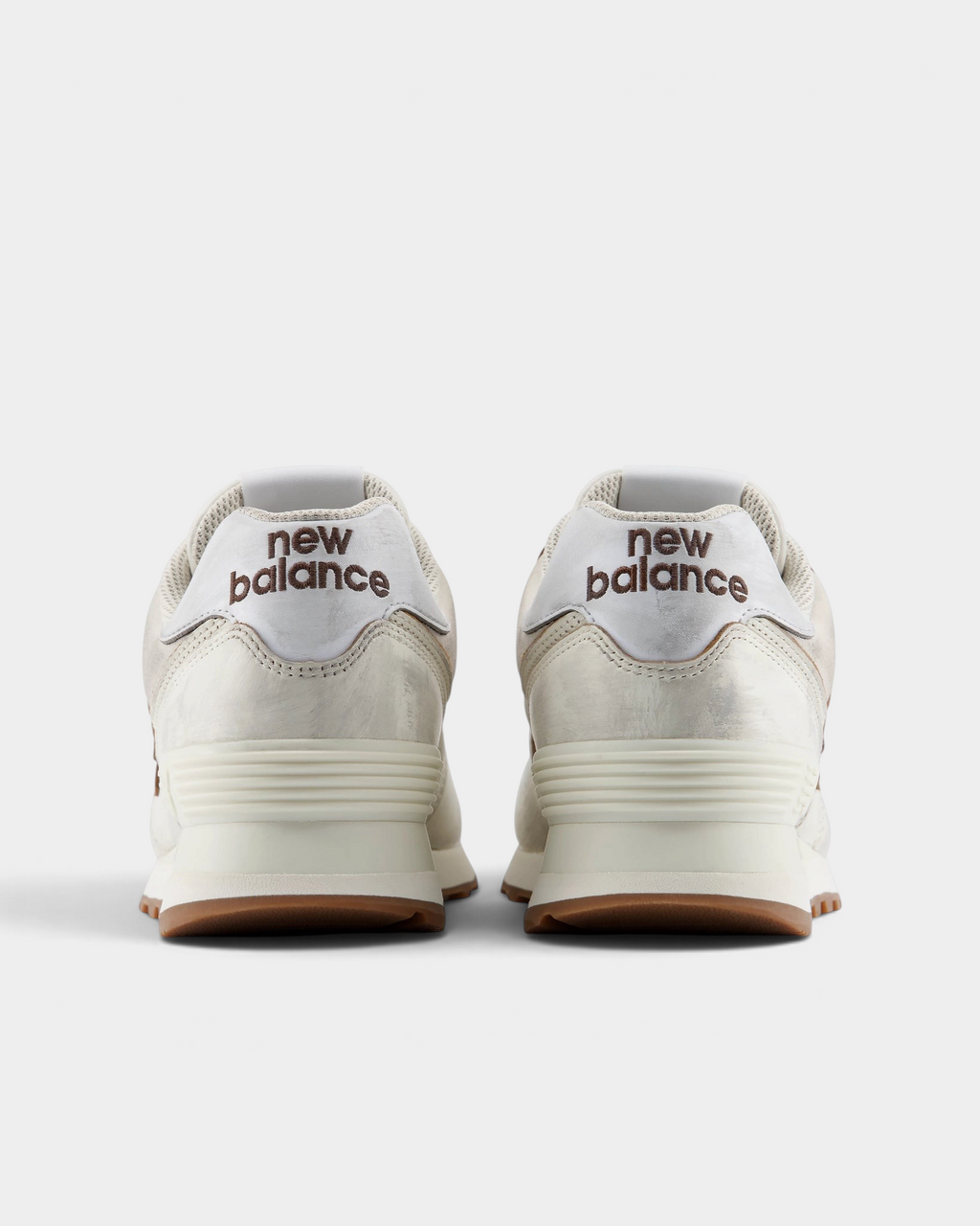 New Balance 574 Shoes in Sea Salt/Breakfast Tea, pair from behind: cream heels with silver heel tabs reading new balance over a cream midsole and gum outsole