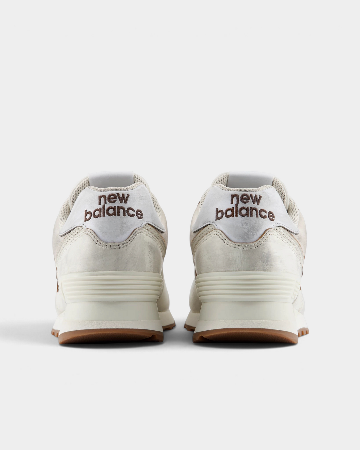 New Balance 574 Shoes in Sea Salt/Breakfast Tea, pair from behind: cream heels with silver heel tabs reading new balance over a cream midsole and gum outsole