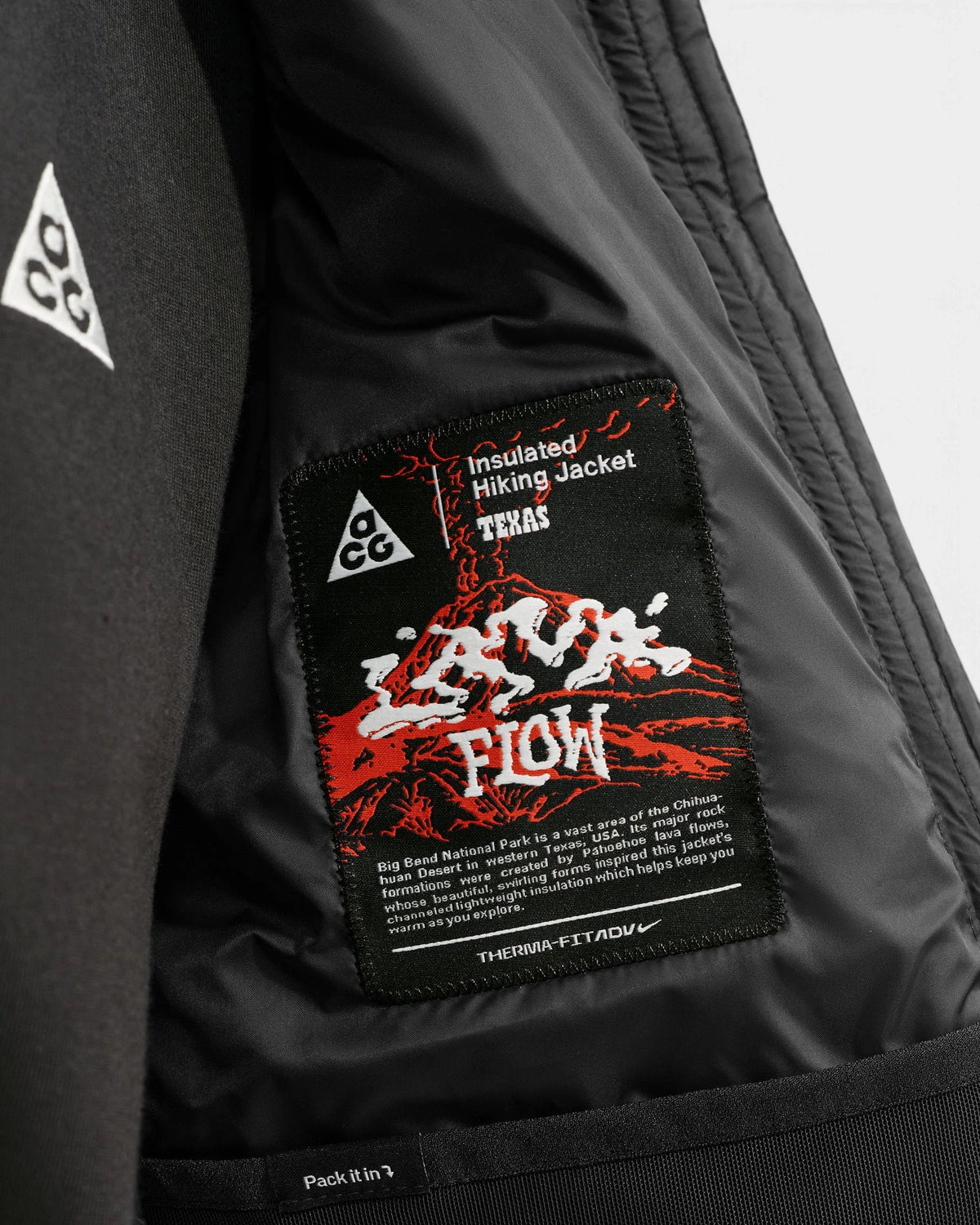 Inside of the Nike ACG Lava Flow Women's Jacket in black and summit white, showing the woven Lava Flow Insulated Hiking Jacket label and the Therma-FIT ADV tag