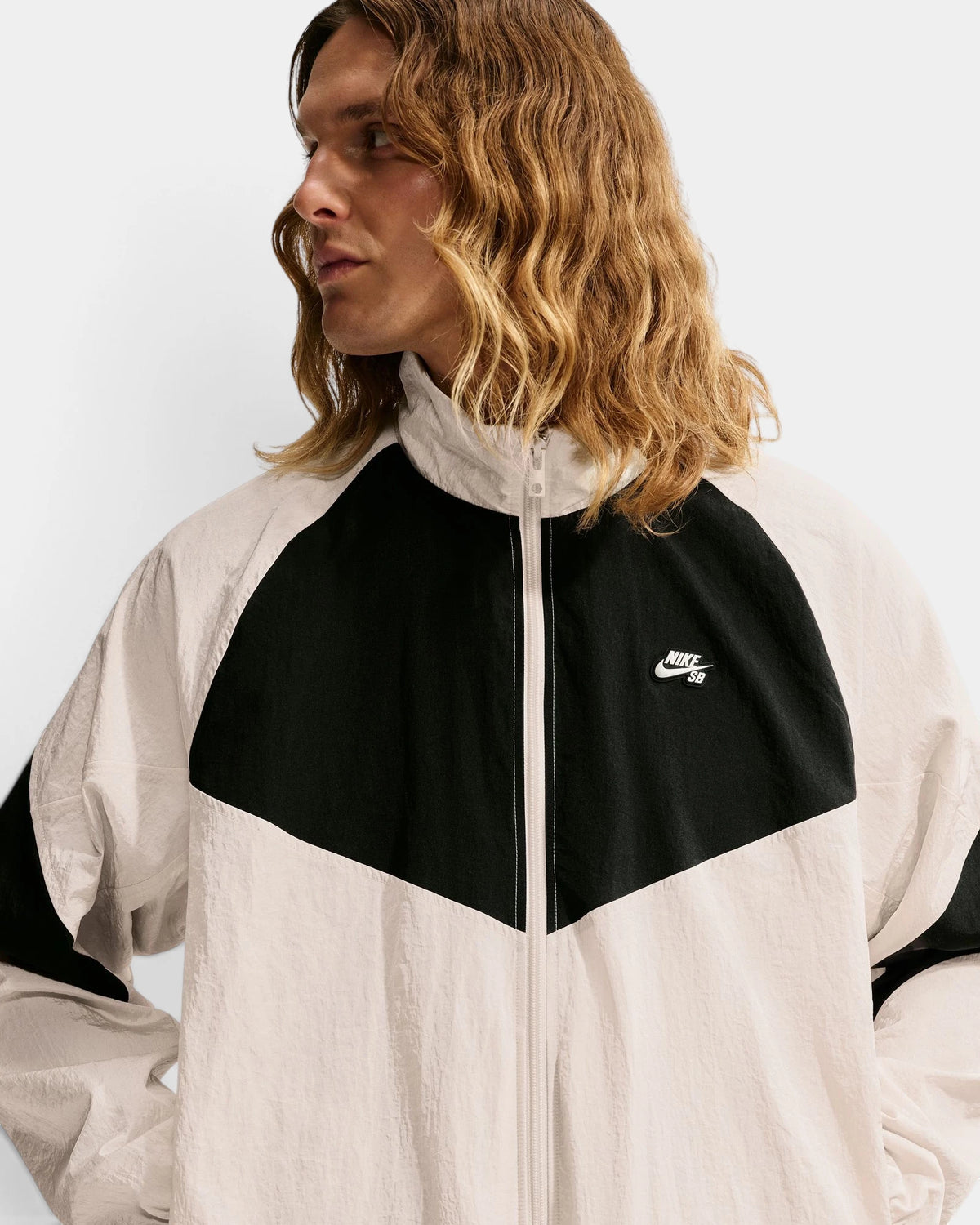 Close-up of the Nike SB Pavan Jacket on a model, with the black chest panel, stand collar and white Nike SB logo