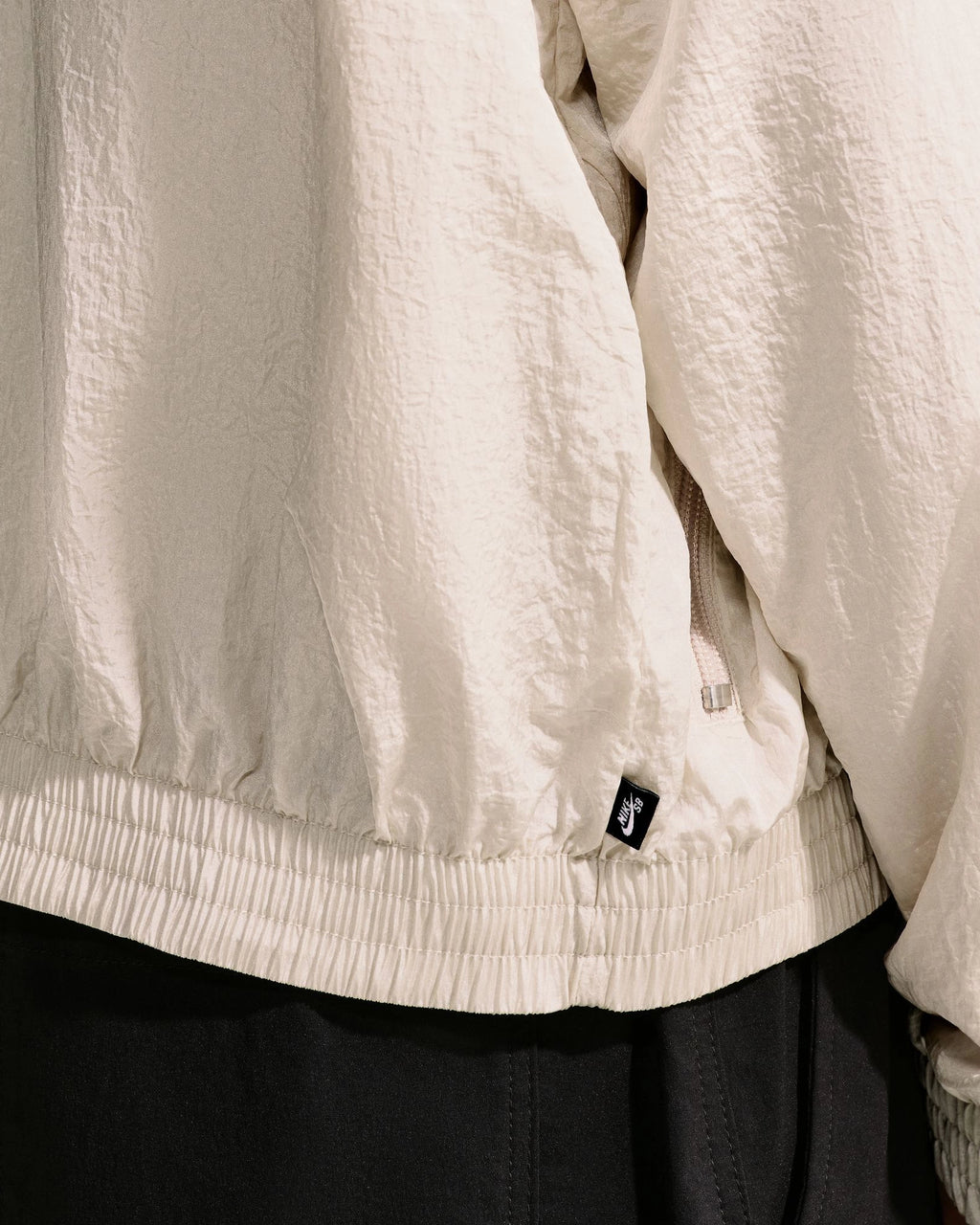 Detail of the elastic waistband and woven Nike SB flag label on the Nike SB Pavan Jacket