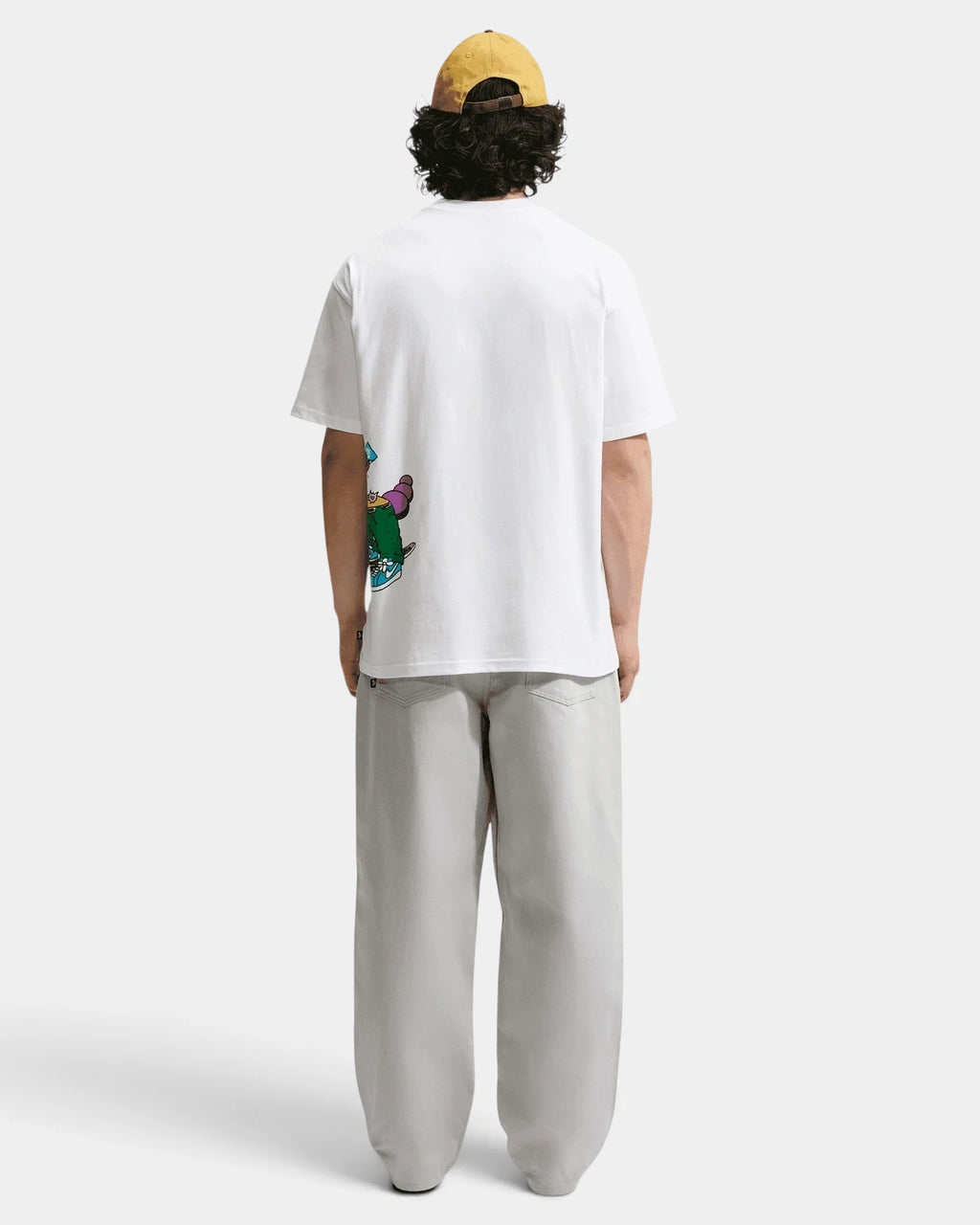 Full-length back view of a model in the white Nike SB Sk8pillar T-Shirt, graphic visible at the side hem
