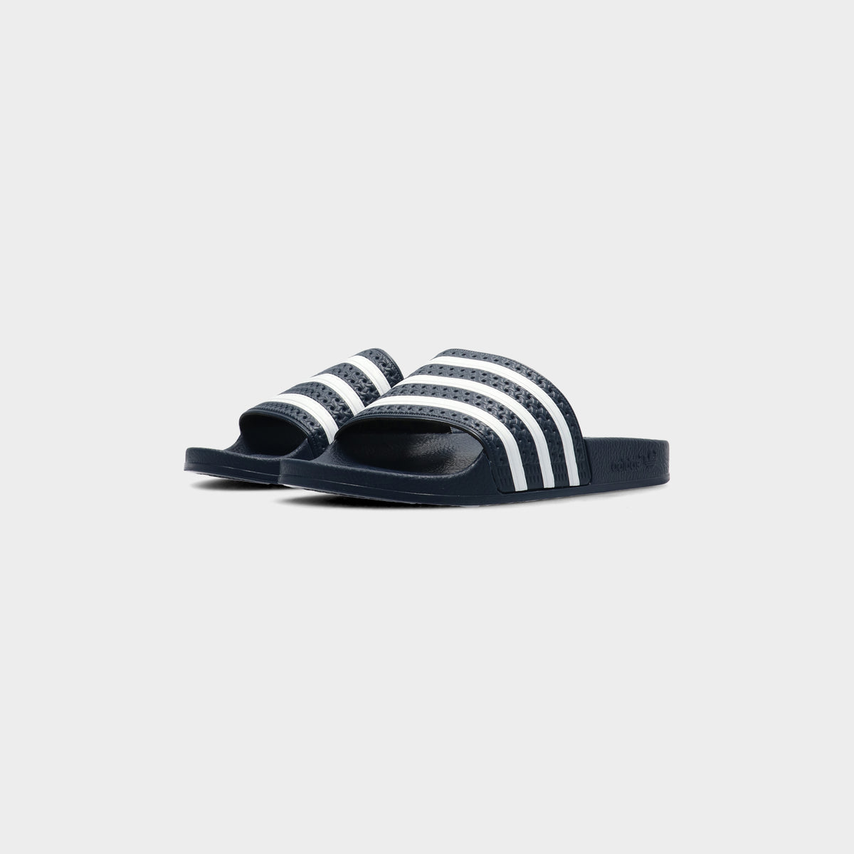Lockwood Avenue pair of adidas Adilette Slides in AdiBlu navy with white 3-Stripes, angled front view