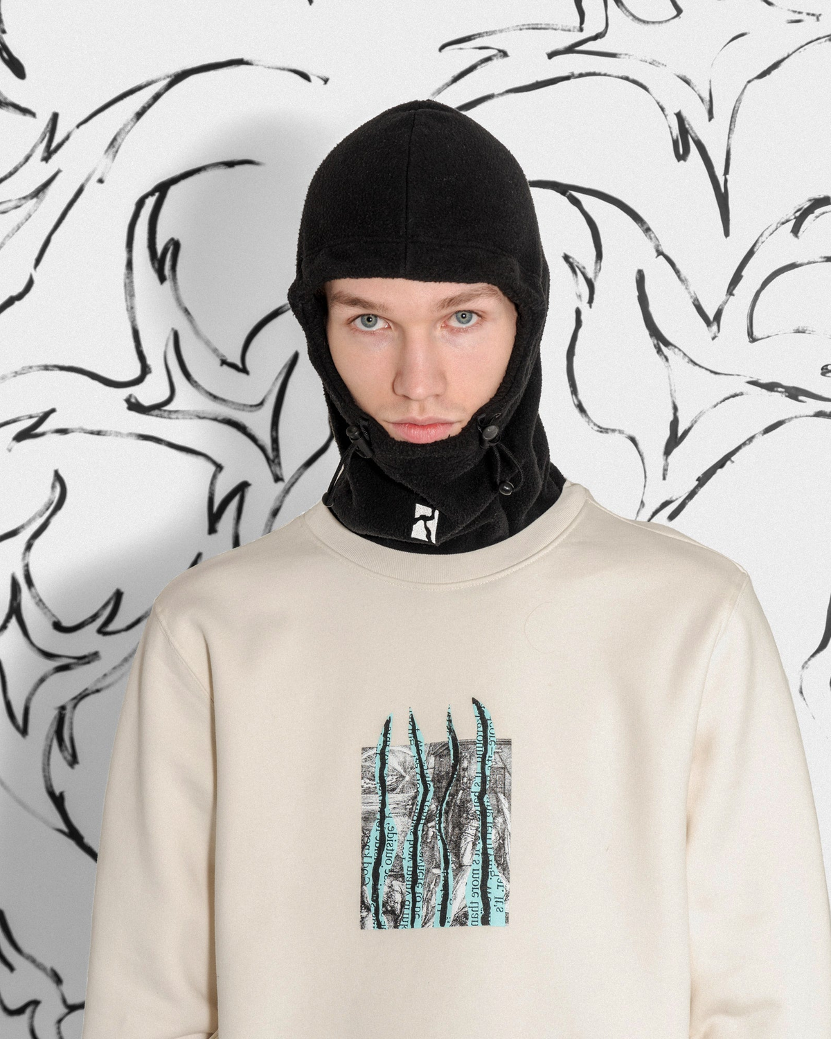 Lockwood Avenue Poetic Collective Fleece Balaclava in black worn by a model, pulled down around the chin over a cream crewneck sweatshirt
