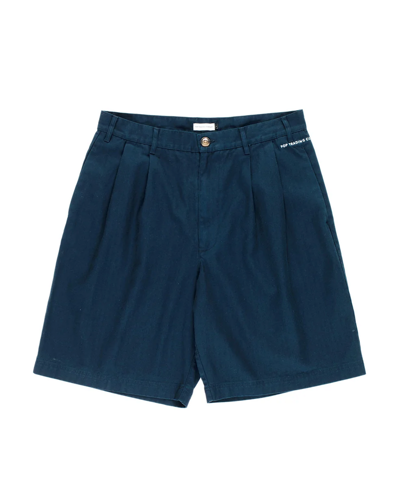 Pop Trading Company Boat Shorts in navy, flat lay front view showing the wide pleated leg, tortoise button and zip fly, and the white embroidered script logo above the left side pocket