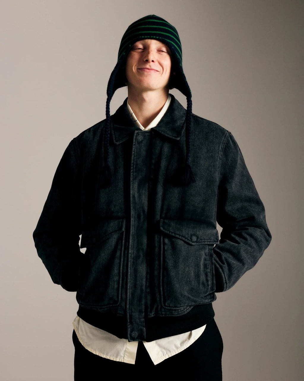 Lockwood Avenue model wearing the Pop Trading Company Reversible Earflap Beanie on the striped navy and juniper side with a dark jacket, front view