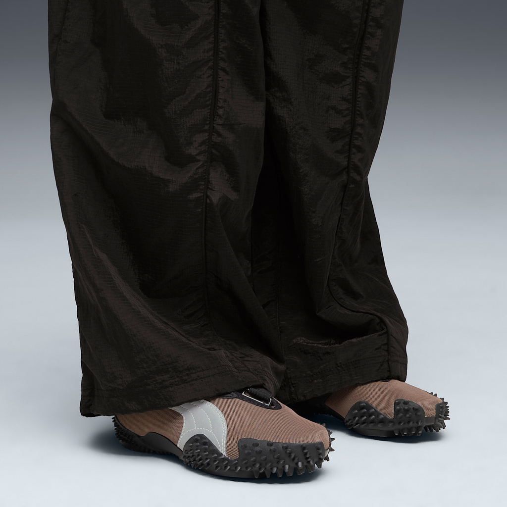 Puma Mostro OG in Dark Clove worn on foot under wide black ripstop trousers