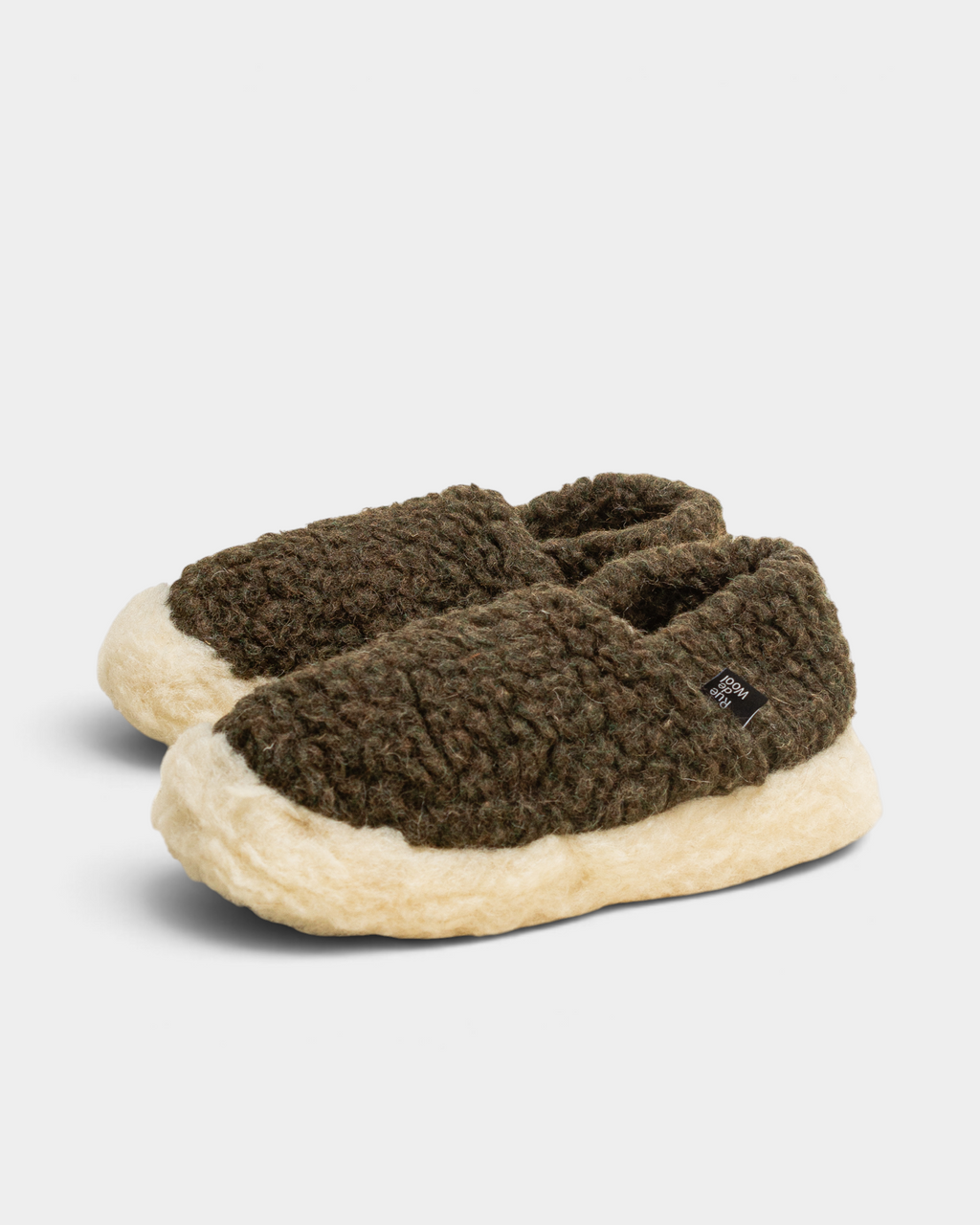 A pair of Rue De Wool The Nordic V2 slippers in dark olive green and natural, angled front view with the small woven label on the side