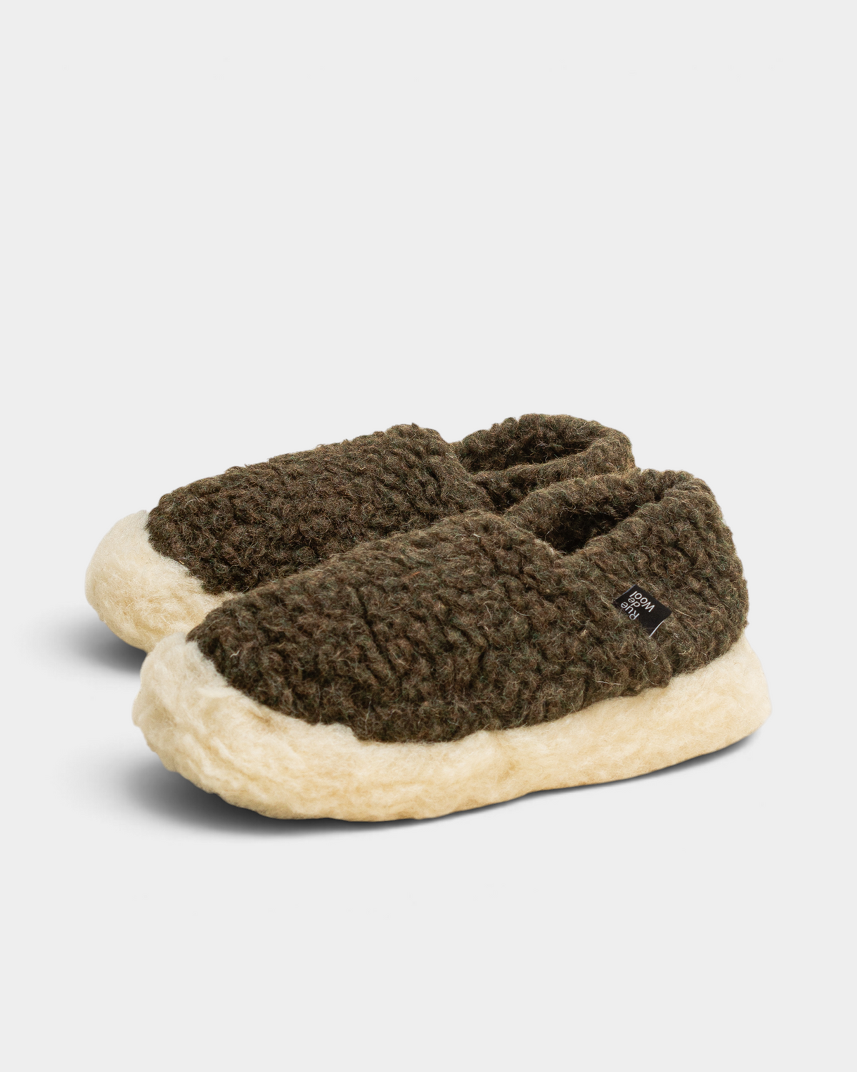 A pair of Rue De Wool The Nordic V2 slippers in dark olive green and natural, angled front view with the small woven label on the side